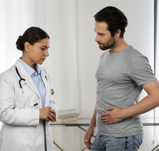 Image of a man holding his left lower abdomen during a medical consultation, indicating discomfort or pain.