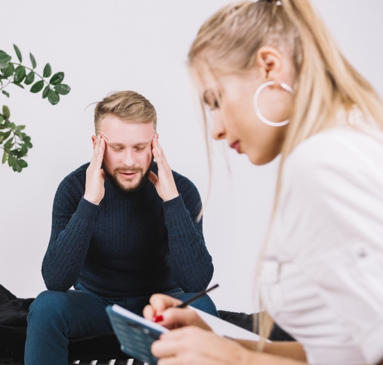 Image of a young female psychologist writing down her observations while assessing a depressed patient during a session.