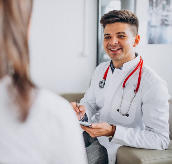 Image of a young male physician smiling at a patient during a consultation.